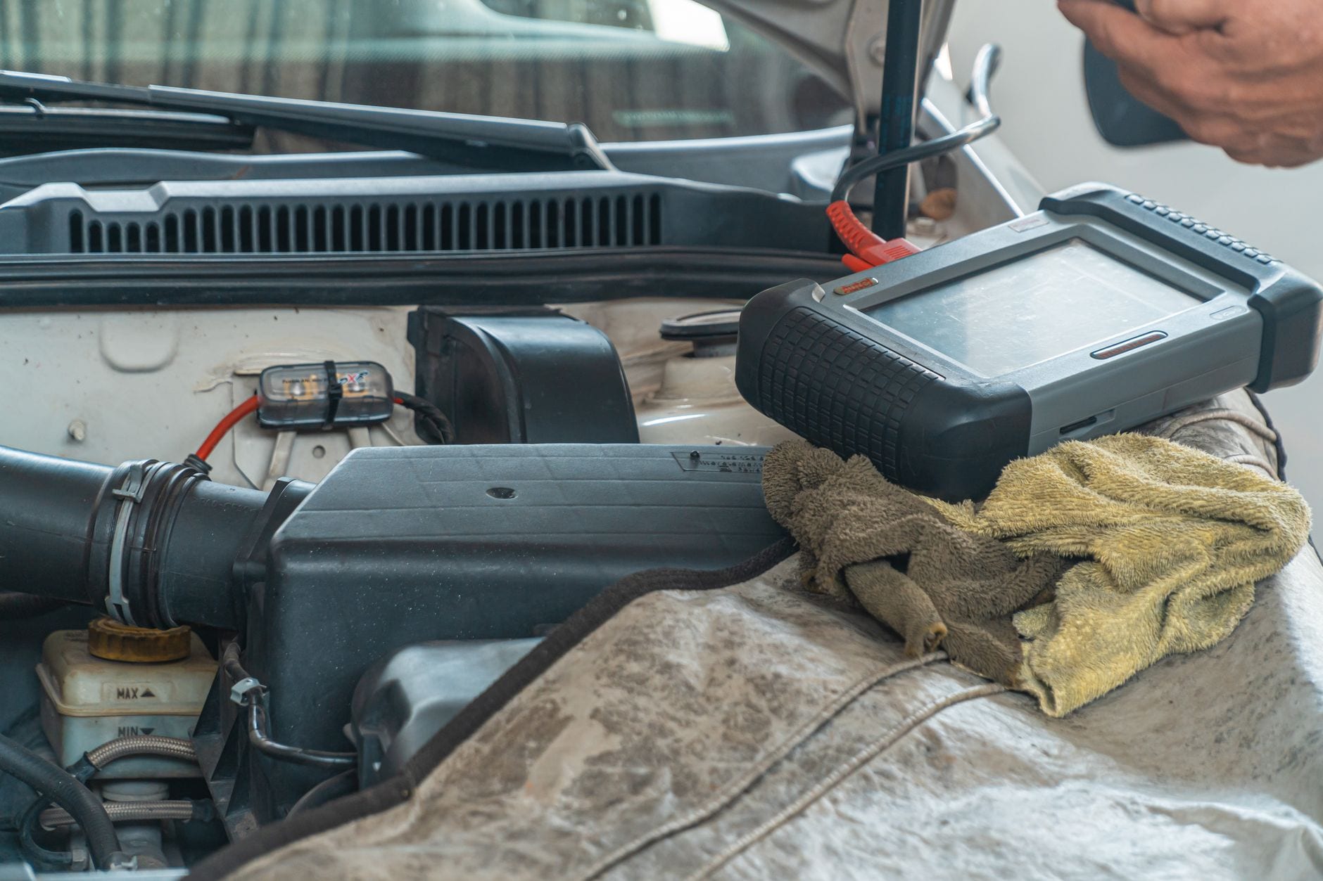 A diagnostic scanner tool connected to a car engine in a repair shop.